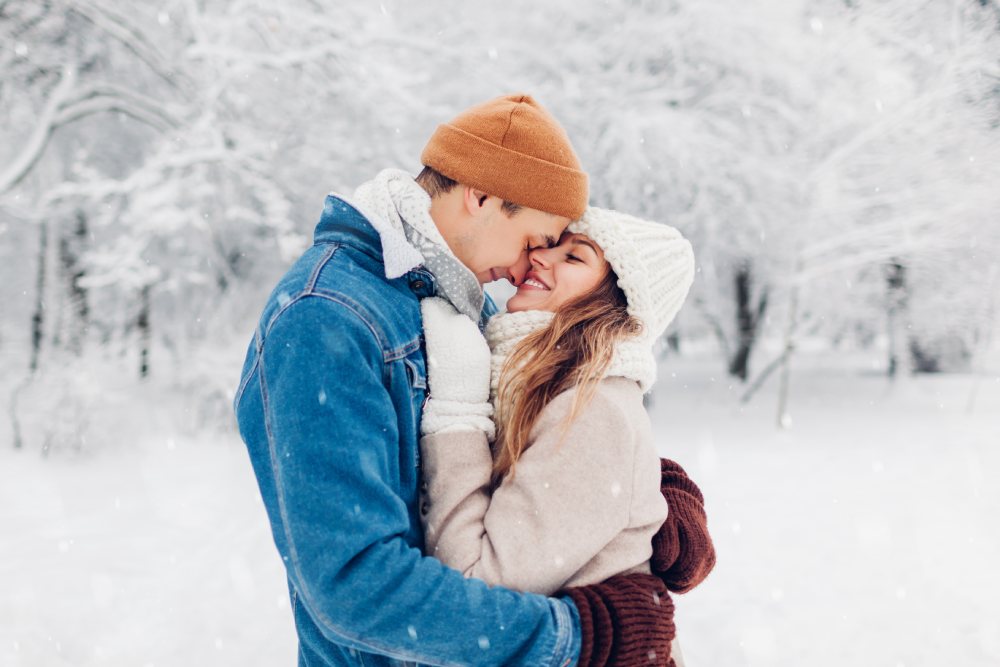 A couple hugs outside in the snow.