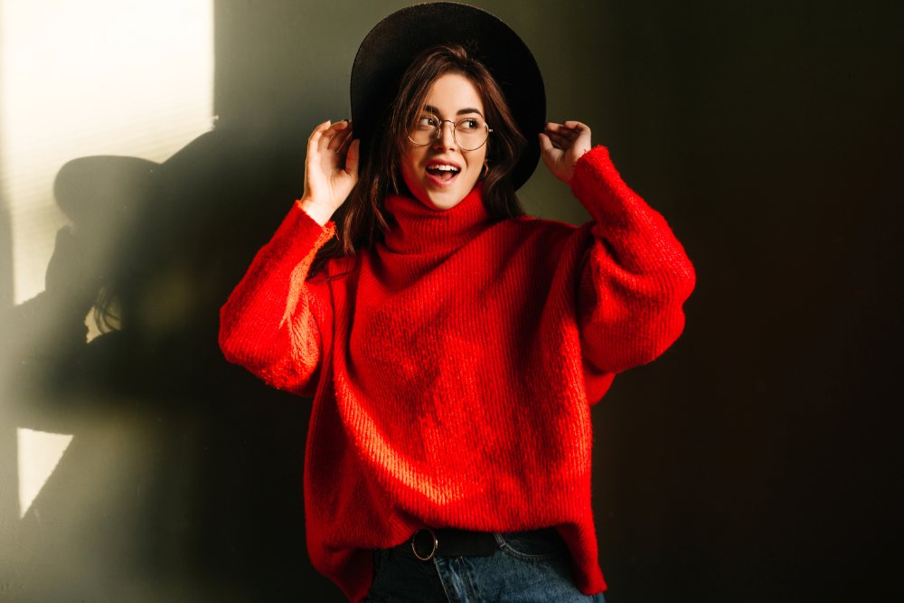Women wears a red oversized sweater and a black hat