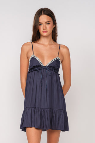 Model wearing a navy blue babydoll mini dress with thin straps from Boho Pink