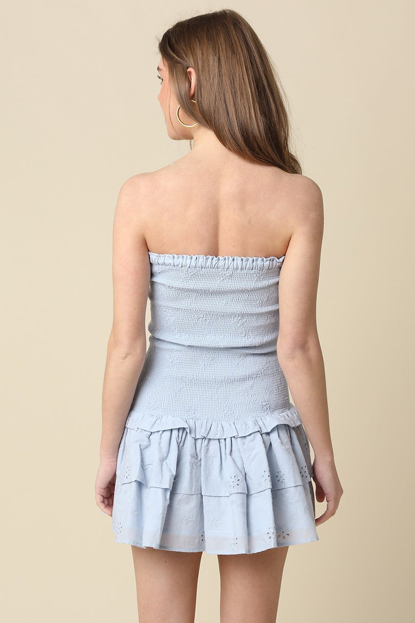 Back view of the light blue Aimee eyelet mini dress featuring a smocked bodice and tiered skirt