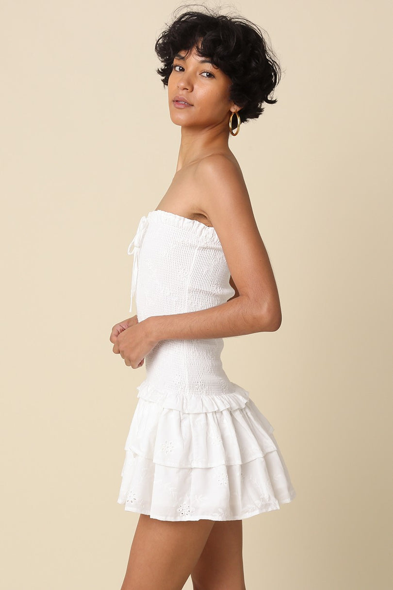Side profile of the Aimee white eyelet dress showing the drop-waist silhouette and tiered ruffle detail