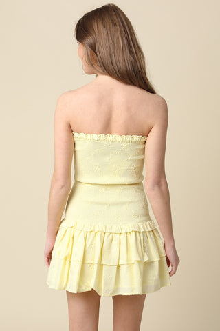 Back view of the Aimee light yellow eyelet strapless dress showing the smocked bodice and tiered skirt