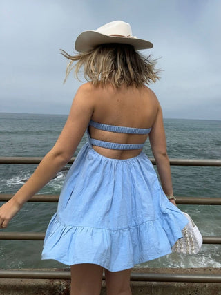 Back view of chambray blue romper dress showing open back and elastic straps 