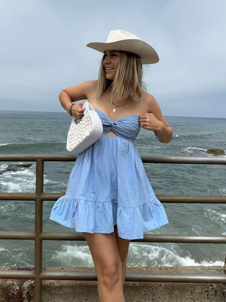 Side view of light blue chambray babydoll romper with twist knot neckline
