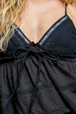 Close-up of the blue and white floral embroidery and crochet lace on the black textured fabric