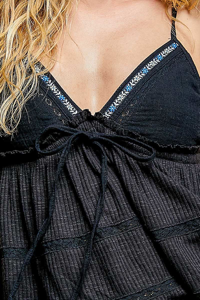 Close-up of the blue and white floral embroidery and crochet lace on the black textured fabric