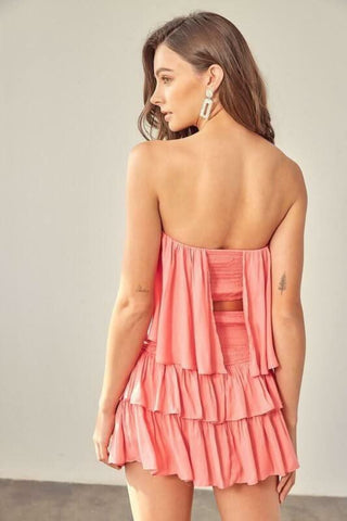Back of the coral strapless ruffle romper featuring a comfortable elastic waist and breezy tiered design