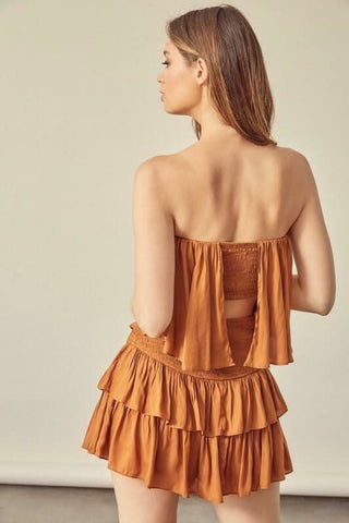 Back of the caramel strapless ruffle romper featuring a comfortable elastic waist and breezy tiered design