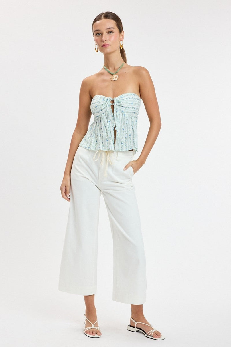 Full body model view of the Briley Blue Floral Strapless Babydoll Top styled with white wide-leg jeans