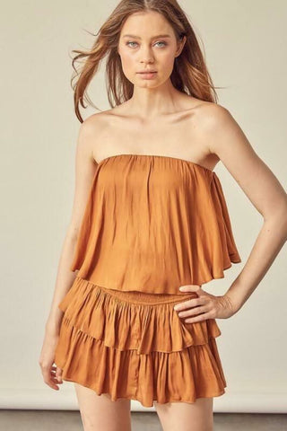 Model wearing the Monaco Caramel Strapless Ruffle Romper, a tiered mini dress style romper for summer vacations