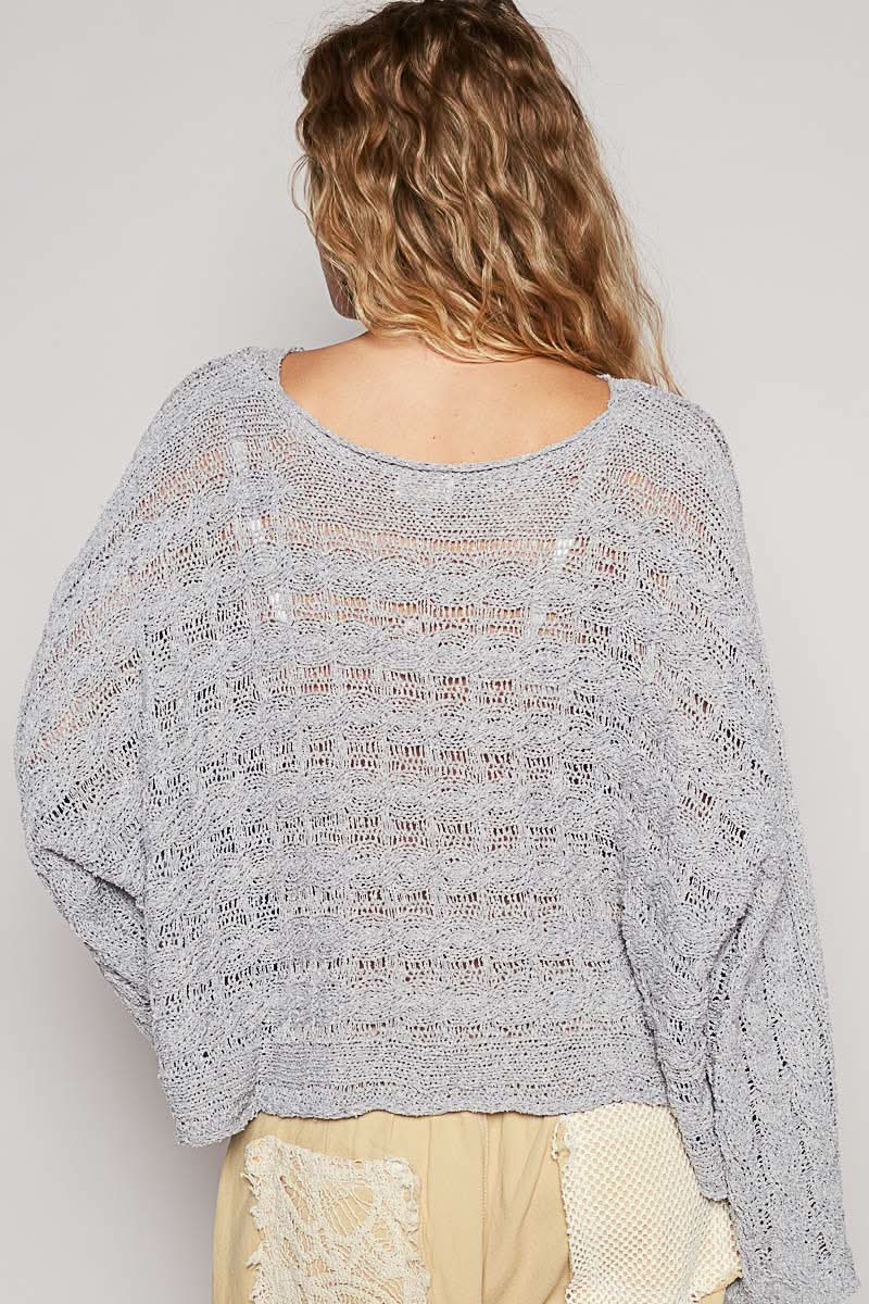 Person wearing a textured gray sweater with text on the back against a plain background