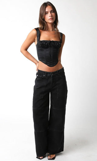 Black satin corset crop top styled with baggy jeans and heels