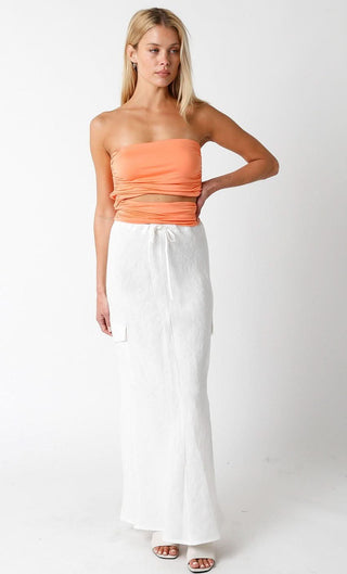 Model wearing the Kaia White Linen Cargo Maxi Skirt with an orange tue top and heels