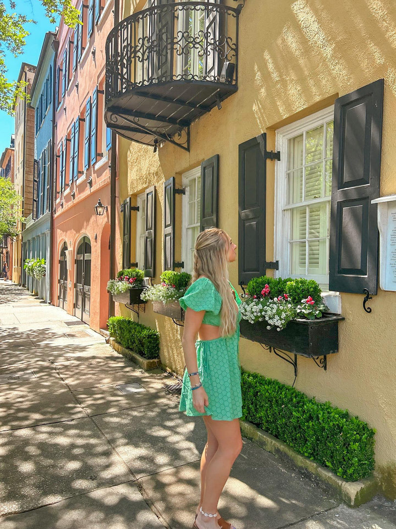 Green puff sleeve mini dress with cutout waist styled on a sunny Charleston street from our green mini dresses collection