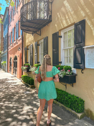 Open back green eyelet mini dress with puff sleeves styled outdoors in natural sunlight