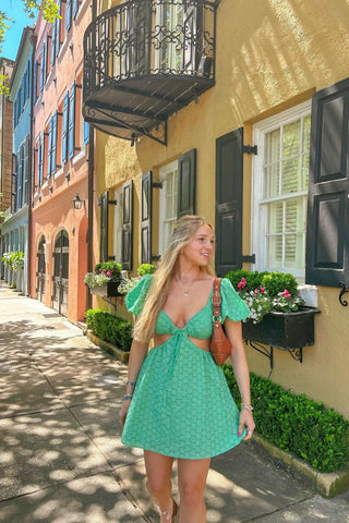 Influencer wearing green puff sleeve mini dress with V-neckline and waist cutout 