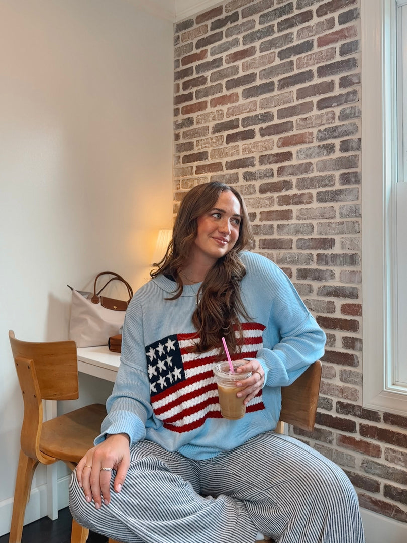 Land of Free light blue American flag sweater worn in a coffee shop setting