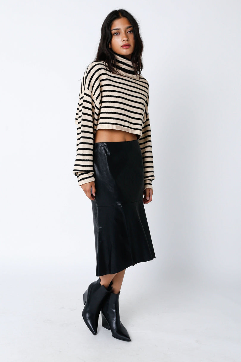 Woman wearing a striped sweater and black leather skirt on a white background