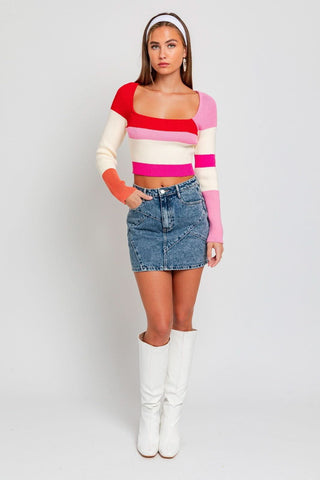 A modell wearing one of our cute sweaters with a mini skirt and white boots