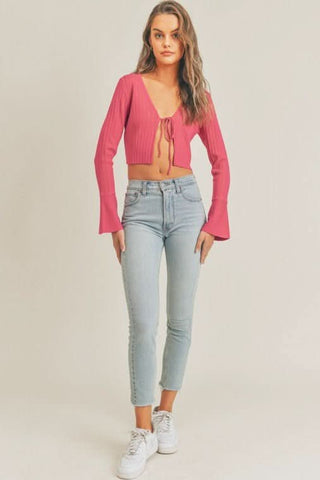 Model wearing LUSH So Many Reasons Pink Tie-Front Long Sleeve Crop Top with light jeans and sneakers
