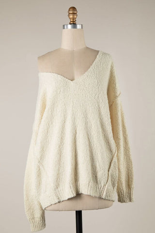 Oversized cream v-neck sweater with relaxed drop shoulder fit on model.