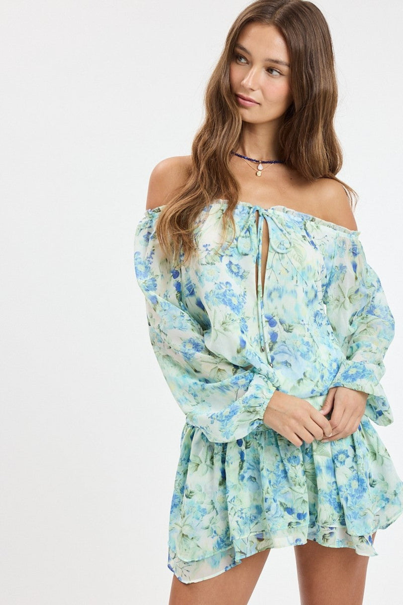 Lifestyle view of the Pixie Blue Watercolor Floral Off-the-Shoulder Romper Dress showing movement and fit