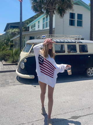Women in the land of free white american flag sweater twirling around outdoors on a sunny day