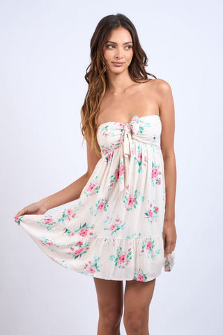 Model wearing a cream and pink rose floral babydoll mini dress with a tiered ruffle hem