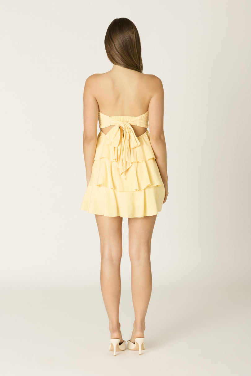 Back view of yellow strapless dress showing decorative tie-back bow and secure elastic strap.