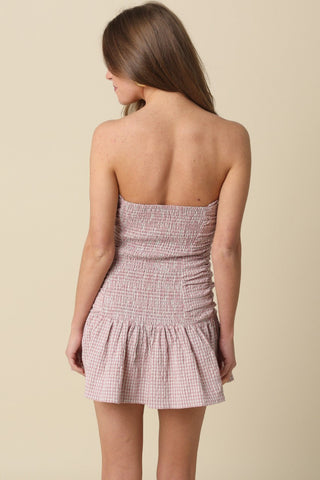 Back view of Taryn Pink Gingham Strapless Mini Dress highlighting the stretchy smocked back panel