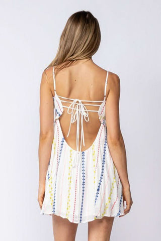 Back view of white embroidered babydoll mini dress with tie back for vacation