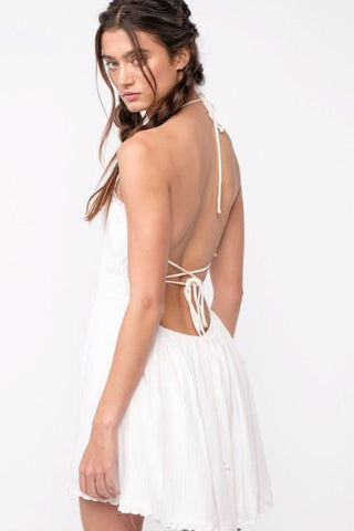 Flowy white halter dress with ruffled hem and open back