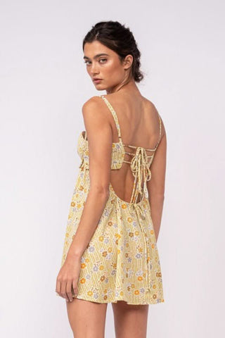 Back angle view of olive floral babydoll mini dress with lace-up detail