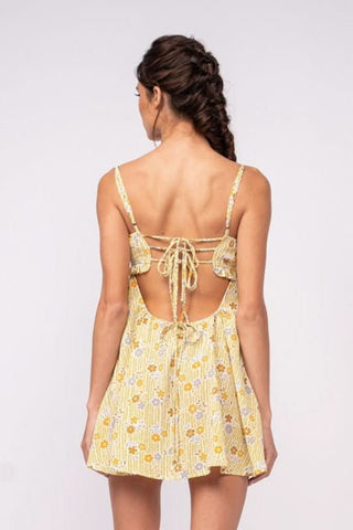 Back view of olive yellow  floral babydoll mini dress with lace-up detail