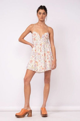 Woman wearing white floral corset cami dress with block heels and pearl jewelry for a bridal shower