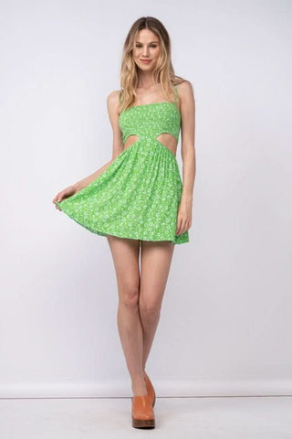 Model wearing a vibrant green and white floral sundress with side cutouts