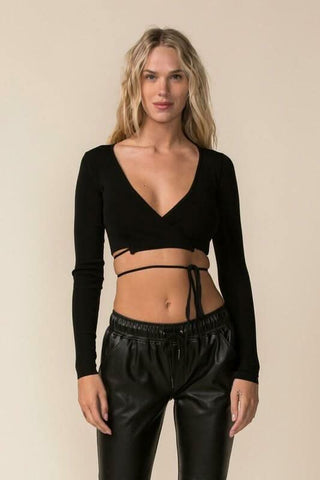 Woman wearing a black wrap cropped sweater top with a surplice neckline and long sleeves