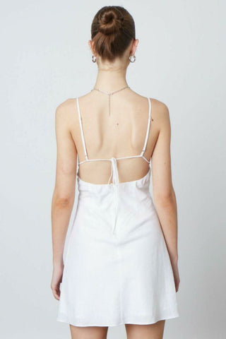 Back view of a white linen-blend mini dress showing the open back