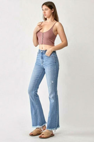 Full length view of a model wearing flare jeans styled with a crop top and sandals"