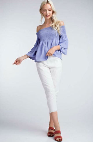 blue off the shoulder top styled with white pants full length view