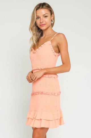 Side view of peach blush smocked bodice and tiered ruffle hem detail