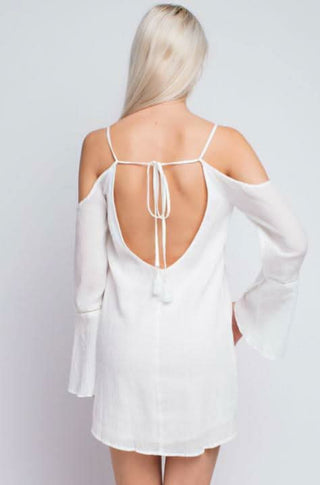 Rear view of the white gauze dress showing the low open back with tassel tie detail.