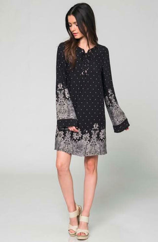 Black long-sleeved bell sleeve shift dress with a border floral print pattern along the hem and cuffs