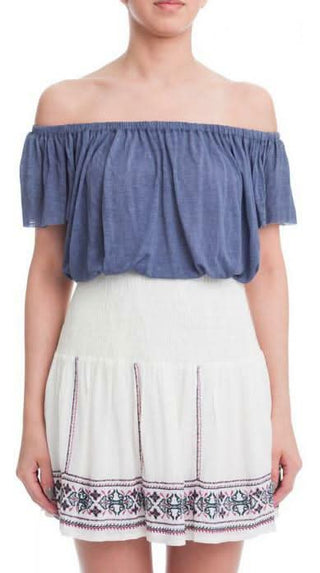 Model wearing the Sophie Ivory Embroidered Smocked Waist Mini Skirt with blue and wine floral detailing.