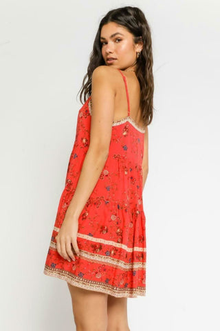 Model wearing red swing babydoll dress for a summer boardwalk look