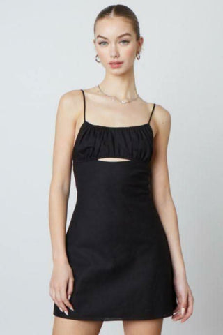 Woman wearing the Luna black A-line mini dress with a ruched bust and cutout