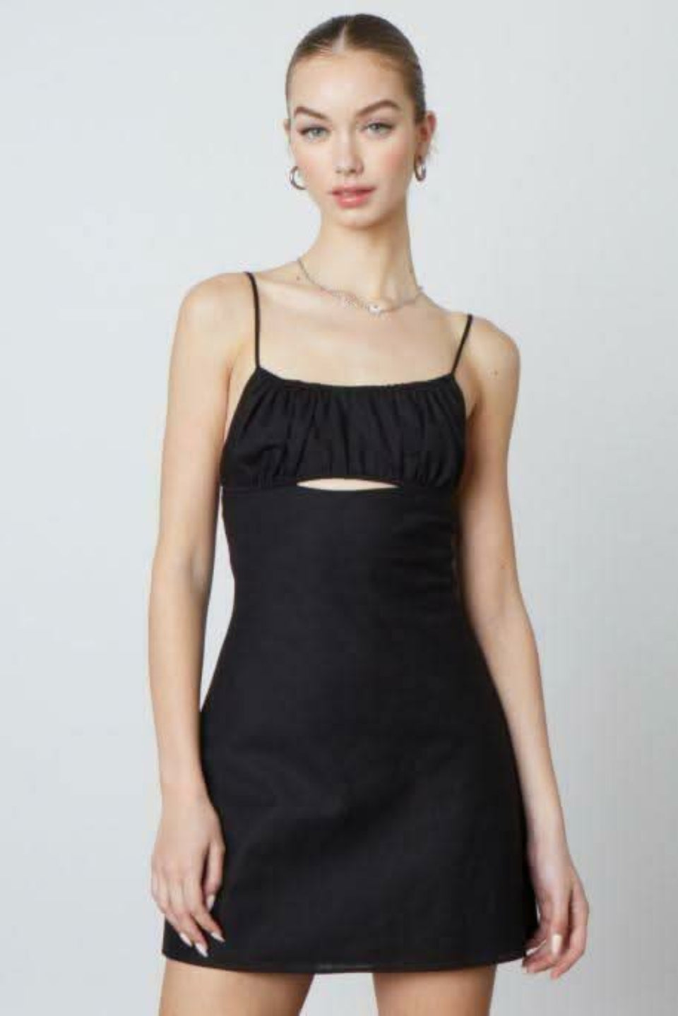 Woman wearing the Luna black A-line mini dress with a ruched bust and cutout