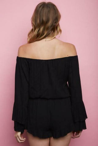 Back view of black boho romper showing off-the-shoulder neckline and ruffled short trim | Boho Pink