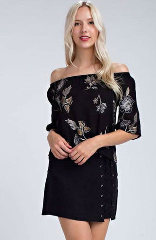 Model wearing an off-the-shoulder floral top with a black mini skirt