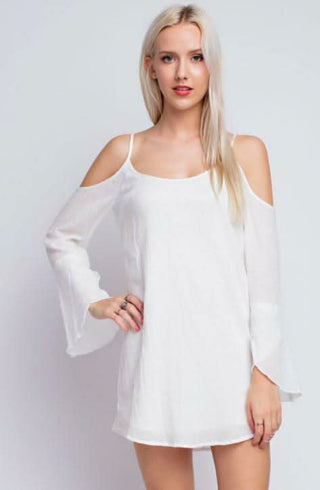 Model wearing the Marina White Bell Sleeve Dress featuring a cold-shoulder shift bodice and long flowy bell sleeves.